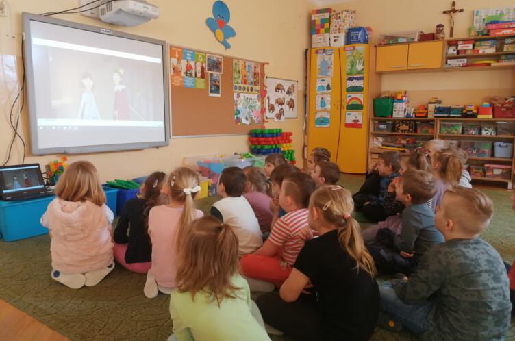 Przedszkolaki oglądające film na ekranie.