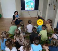 An eco-manager reading a book to a group of children.