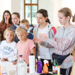 An eco-manager with a group of children conducting physical experiments.