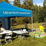 The eco-manager's booth is in a blue tent, next to a large board game spread out on the grass.
