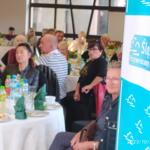 Competition laureates sitting at tables with pastries and beverages.