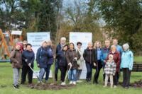 A group of 16 participants on a walk with seedlings and shovels against the backdrop of promotional roll-up banners.