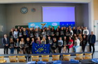 A group of several dozen eco-advisors standing on the stage with postgraduate diplomas in their hands.