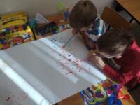Two boys painting a picture at the table.