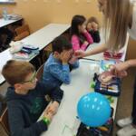 A group of children painting pictures on the table under the supervision of an eco-manager.
