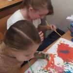 A group of girls painting pictures on the table.