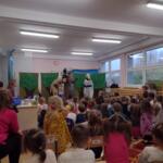 Children sitting on the floor at school and watching a performance.