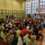 Children sitting on the floor at school and watching a performance.