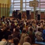 Children sitting on the floor at school and watching a performance.