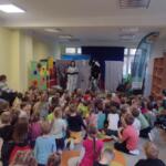 Children sitting on the floor at school and watching a performance.