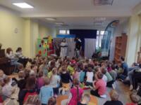 Children sitting on the floor at school and watching a performance.