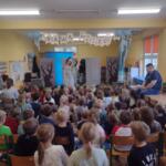 Children sitting on the floor at school and watching a performance.