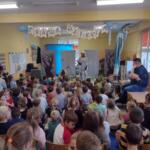 Children sitting on the floor at school and watching a performance.