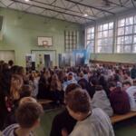 Children sitting on the floor at school and watching a performance.