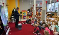 A group of preschoolers sitting on the floor and listening to the eco-manager's presentation.