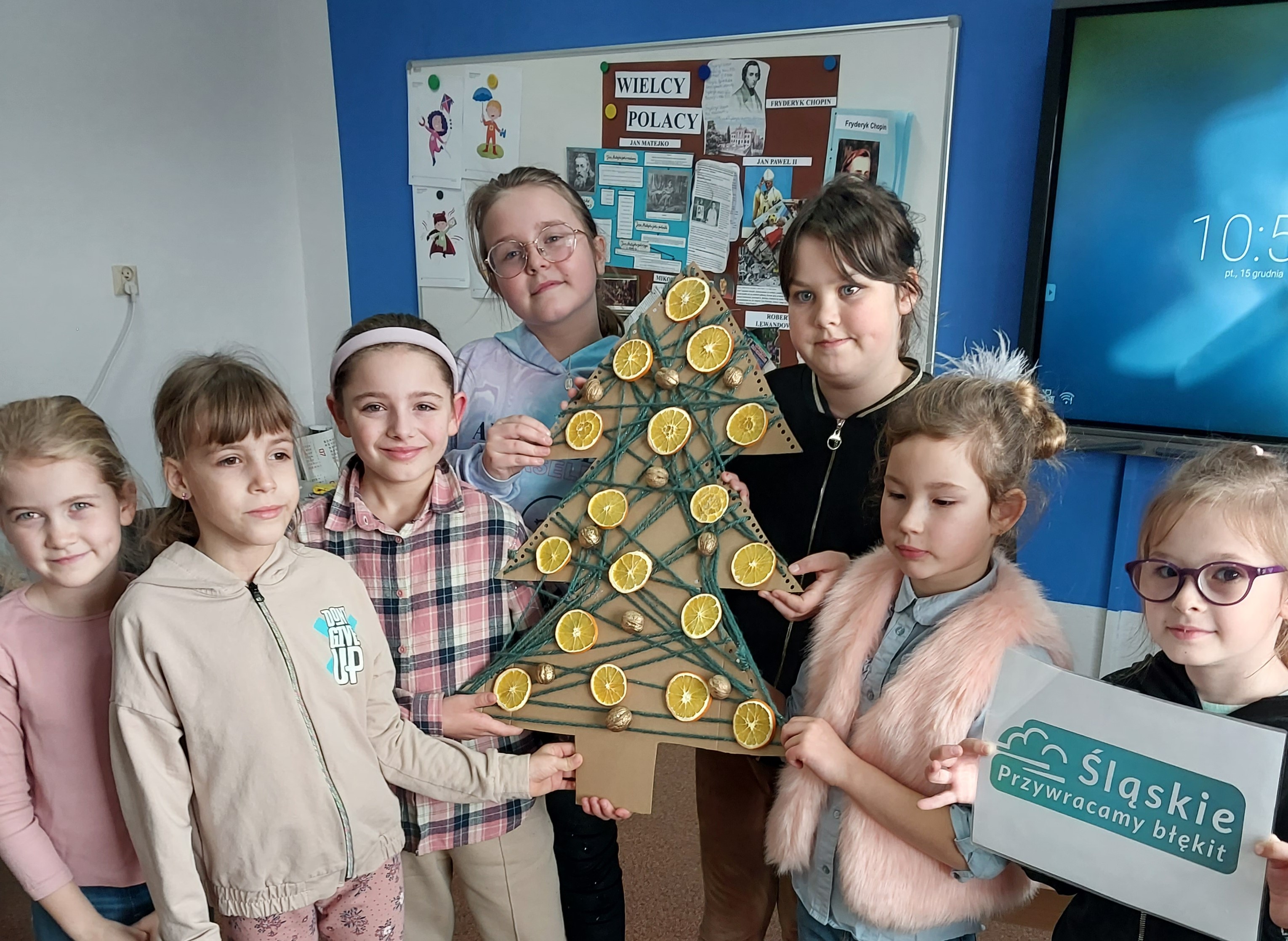 Grupa dzieci prezentująca ekoozdoby choinkowe.