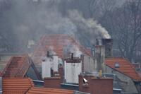 Dachy budynków komunalnych z dymiącymi kominami.